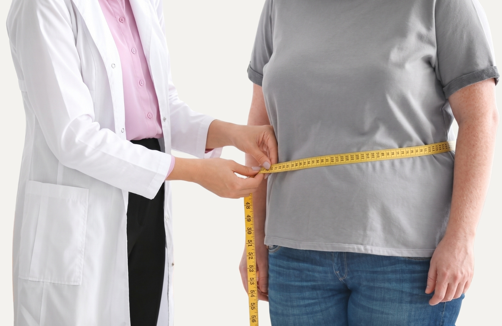 Clinician uses a measuring tape around a patient's waist to assess waist size.