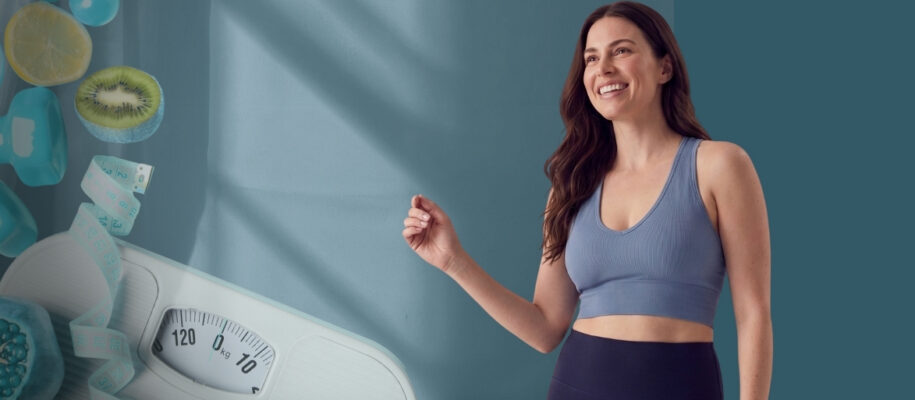 Smiling woman in a blue sports bra and dark leggings stands beside a weighing scale and healthy-quiz props on the left, against a teal background.